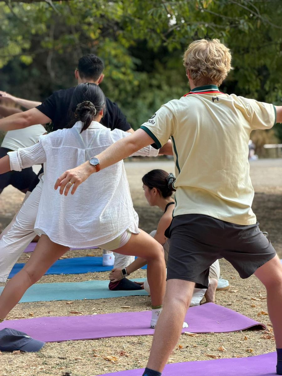 Zu kneeling to adjust a student's foot during warrior two