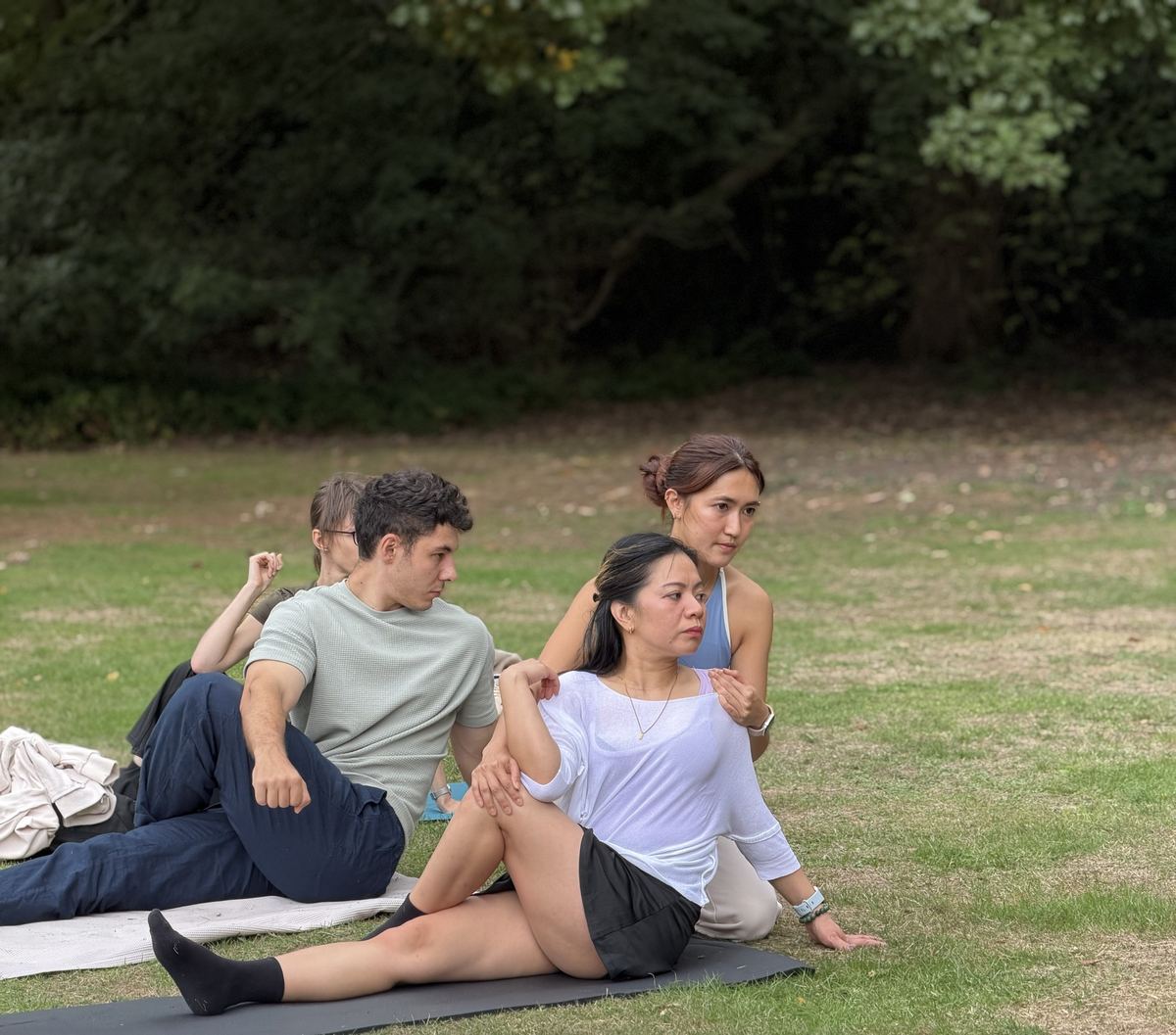 Zu gently guiding a student's shoulder in a seated twist