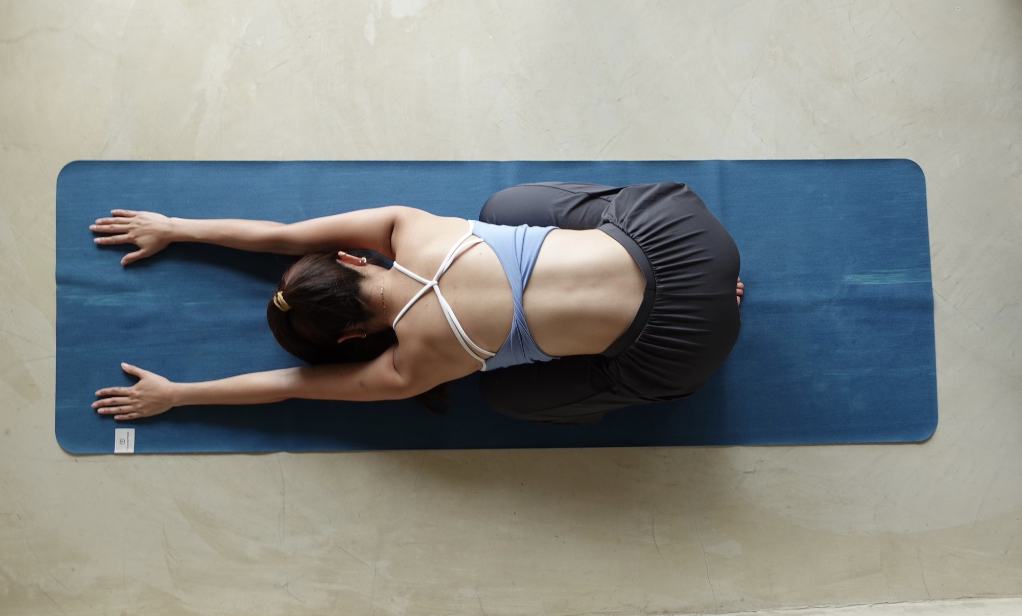 Overhead view of Zu resting in child's pose with arms reaching forward