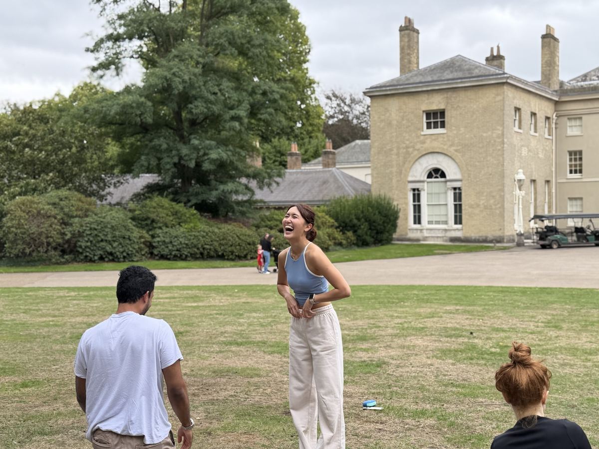 Zu laughing with students on the lawn in front of a Georgian house