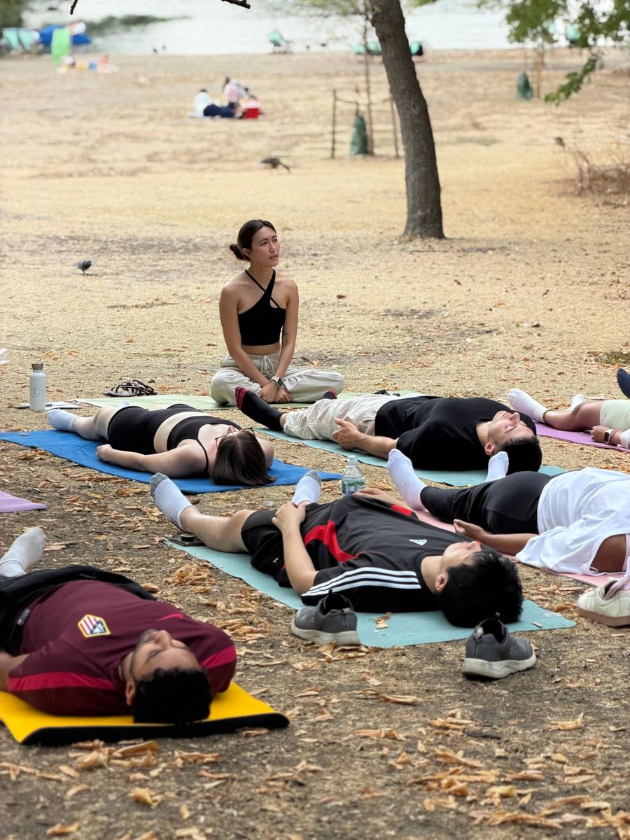Students resting in savasana while Zu sits at the front